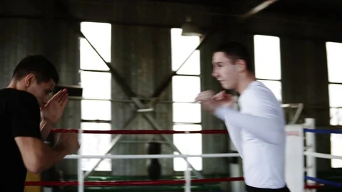 The young boxer reflects the attacks of his opponent on the boxing ring in gym Stock Footage 102721842