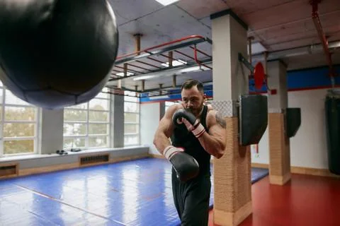 Young boxer striking a blow , trainig at modern gym Stock Photos
