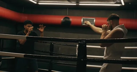 A young boxer with a trainer in the ring is training with a medicine ball. Video stock 275278622