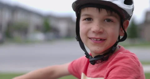 Young boy 6 years old prepares to ride bike wearing helmet - looks towards ca Stock Footage 219650013