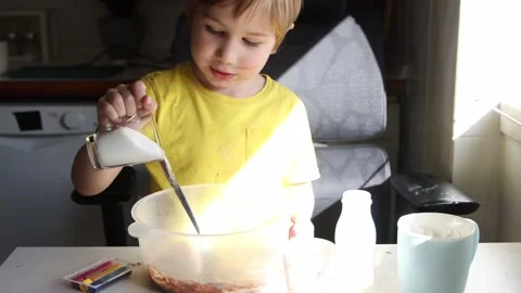 Young boy adding sugar to cake mix in kitchen Stock Footage 316372798