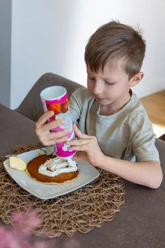 Young boy adding whipped cream to pancake. Young boy adding whipped cream to Stock Photos