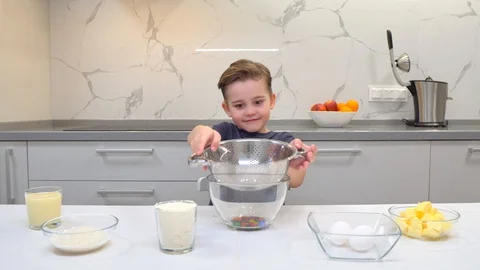 Young boy alone in the kitchen, making a huge mess with flour having fun while Video stock 128834723