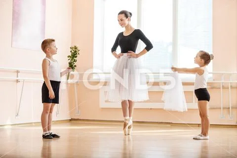 Young boy and girl giving flowers and veil to older student Stock Photos