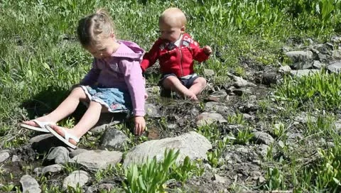 Young boy and girl play in mountain stream Stock Footage