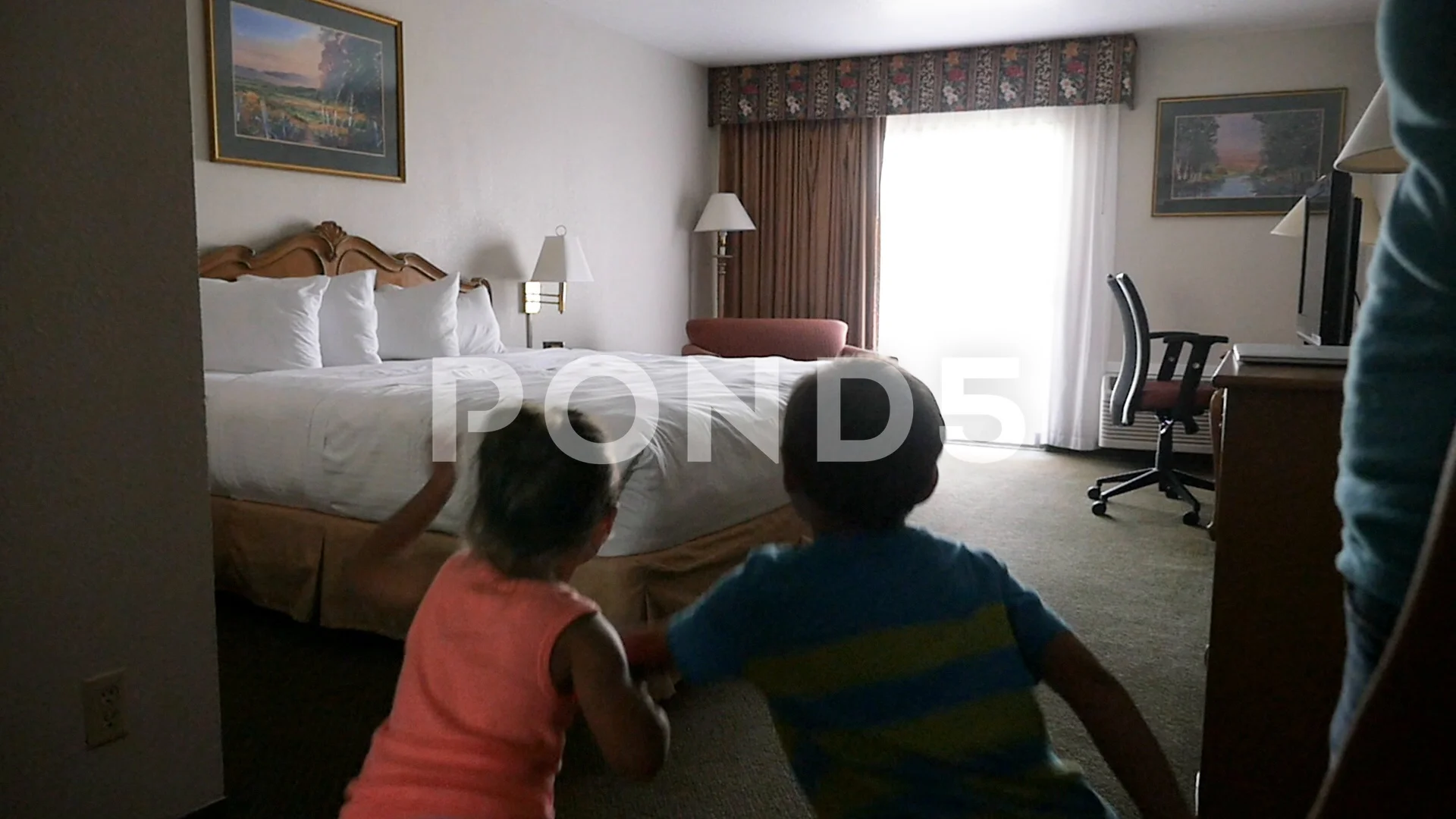 young boy and girl run into room and jump on hotel bed slow motion