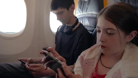 Young Boy and Girl Using Headphones to Play Games on Mobile Devices While Stock Footage 301911364