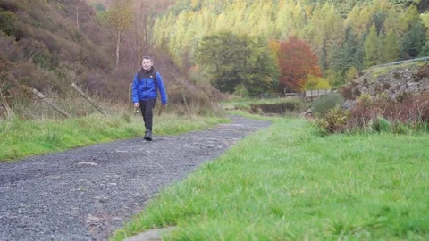 A young boy, with backpack camera and tripod in hand, walking through a tra.. Stockbeeldmateriaal 254803253