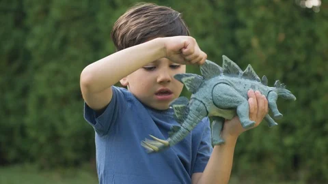 Young boy in backyard and playing with toy dinosaur Vídeos de archivo 119991367