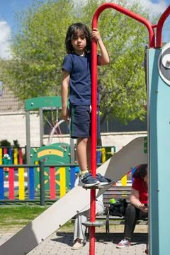 Young boy balancing on a red pole at the playground Stock Photos