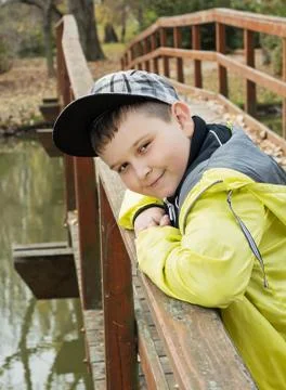 Young boy in baseball cap standing on the bridge and smiling Stock Photos