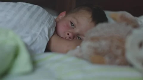 Young boy on bed embracing his stuffed toy and gradually dozing off calm Stock Footage 284673448