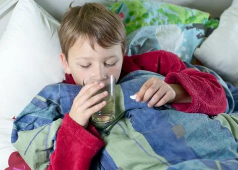 Young boy in bed taking his medicin Stock Photos