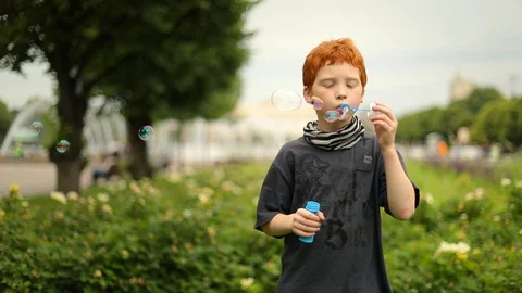 Young boy blowing bubbles in the park, slow motion Vídeos de archivo 98027311