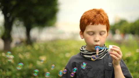 Young boy blowing bubbles in the park, slow motion Stock Footage 98027327