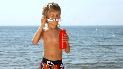 Young boy blowing soap bubbles on the beach Stock Footage 55632557