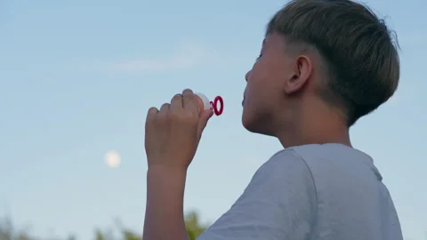 Young Boy Blowing Soap Bubbles Outdoors at Sunset 库存影片 339031764