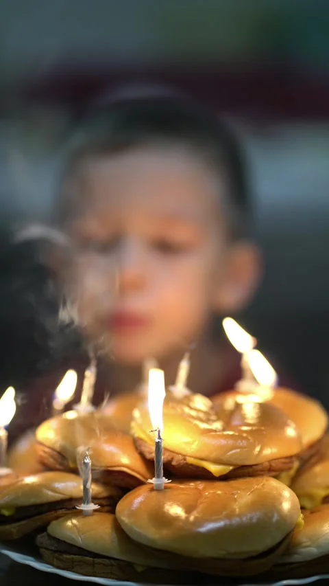 A young boy blows out the candles on a festive birthday cake made entirely of Vídeo Stock 348790146