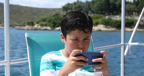 Young boy on boat using smartphone 3 Stock Footage 109430033