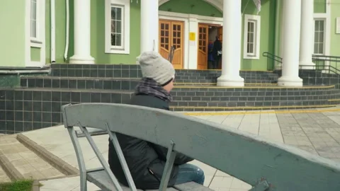 Young boy with book in hand sitting on grey bench stands up Stock Footage 182456155