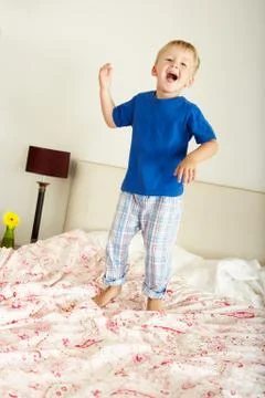 Young boy bouncing on bed Stock Photos
