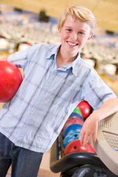 Young boy in bowling alley holding ball and smiling Stock Photos