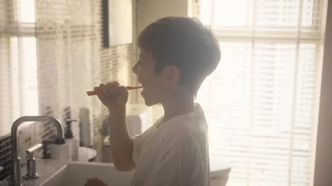 Young boy brushing his teeth with a toothbrush in a bright bathroom at home 스톡 동영상 346473906
