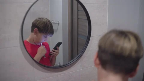 Young Boy Brushing Teeth While Using Phone in The Bathroom Stock Footage 340291209