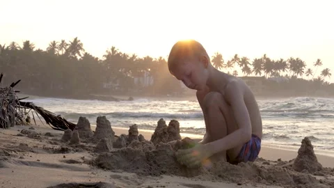 Young boy building sandcastles on beach at sunset Stock-Footage 310545476
