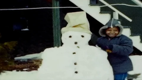 Young boy builds snowman in frontyard at home 1950s vintage film home movie 4846 Video stock 89102089