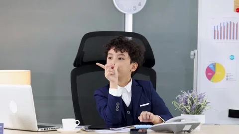 Young Boy in Business Suit Using Calculator and Pointing in Office Stock Footage 335685860