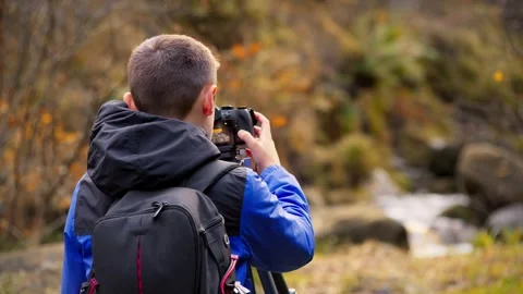 A young boy, camera and tripod, photographs a tranquil autumn-winter woodla.. 库存影片 254805091