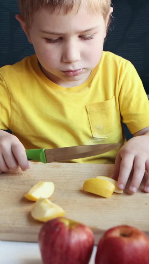 Young boy carefully cutting apples on wooden board Stock Footage 327132683