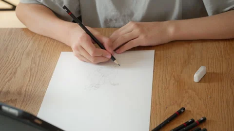 A young boy carefully practicing drawing skills, sketching a character on paper Stock Footage 315289772