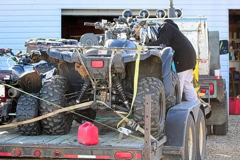 A young boy checking straps for quads on a trailer Stock Photos