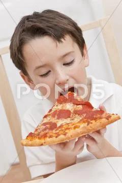 Young boy child eating slice of pizza Stock Photos