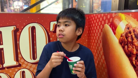 Young Boy Child Siting &amp; Enjoys Eating Dairy Queen Ice Cream In Cup Stock Footage 247431947