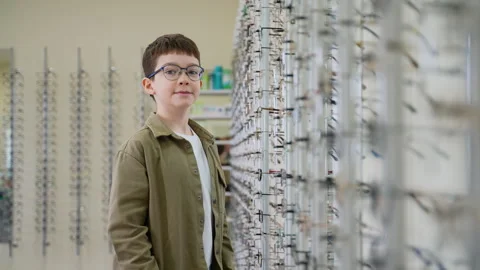 Young boy choosing eyeglasses in optical store Stock Footage 310811684