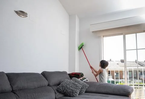 Young boy cleaning wall with long broom Stock Photos