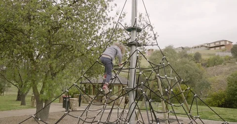 Young boy climbing down playground climbing equipment in a park Video stock 95852299