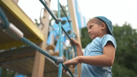 Young boy climbing on rope. Boy is climbing ladder on playground. Boy plays a Stock Footage 316686133