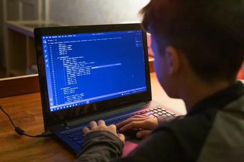 Young boy coding on laptop at night Stock Photos