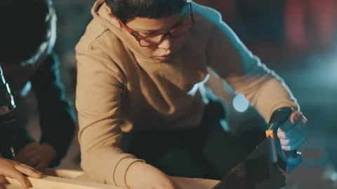 Young boy concentrating while sawing wood in a workshop Stock Footage 329543821
