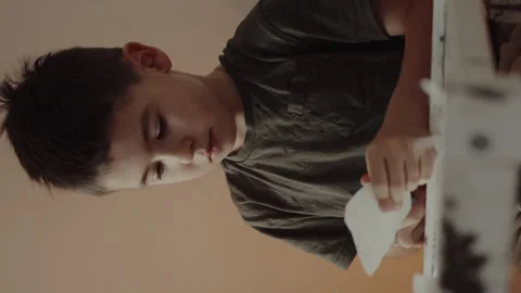 A young boy is concentrating while using a marker to draw on a piece of paper Stock Footage 276108406