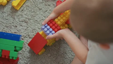Young boy constructs train using colorful pieces with focused attention. Child Stock Footage 331948473