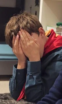 Young boy covers face with hands Stock Photos