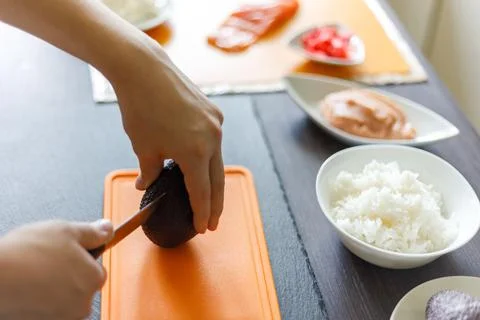 Young boy cutting avocado preparing sushi at home Stock-Fotos