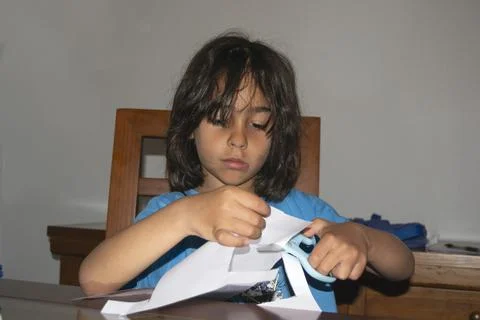 Young boy cutting paper with scissors at home Foto stock