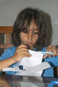 Young boy cutting paper with scissors, developing creativity and motor skills Foto stock