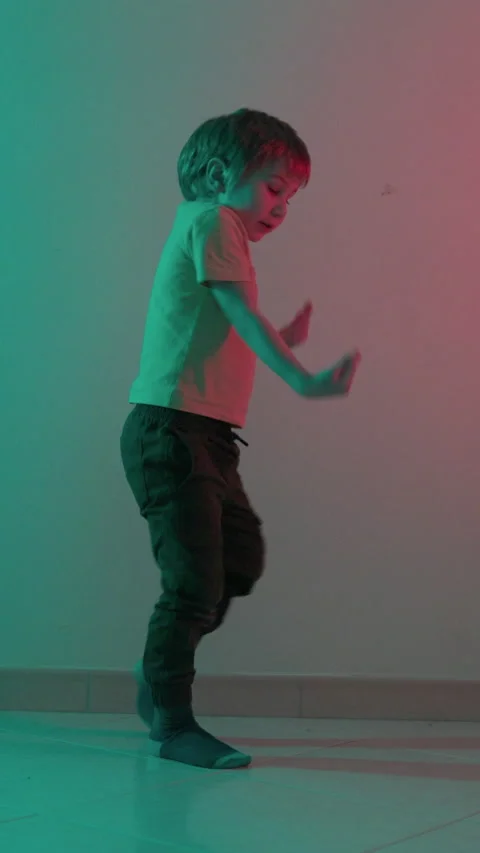 Young boy dancing freestyle in teal and pink lighting Stock Footage 326769221